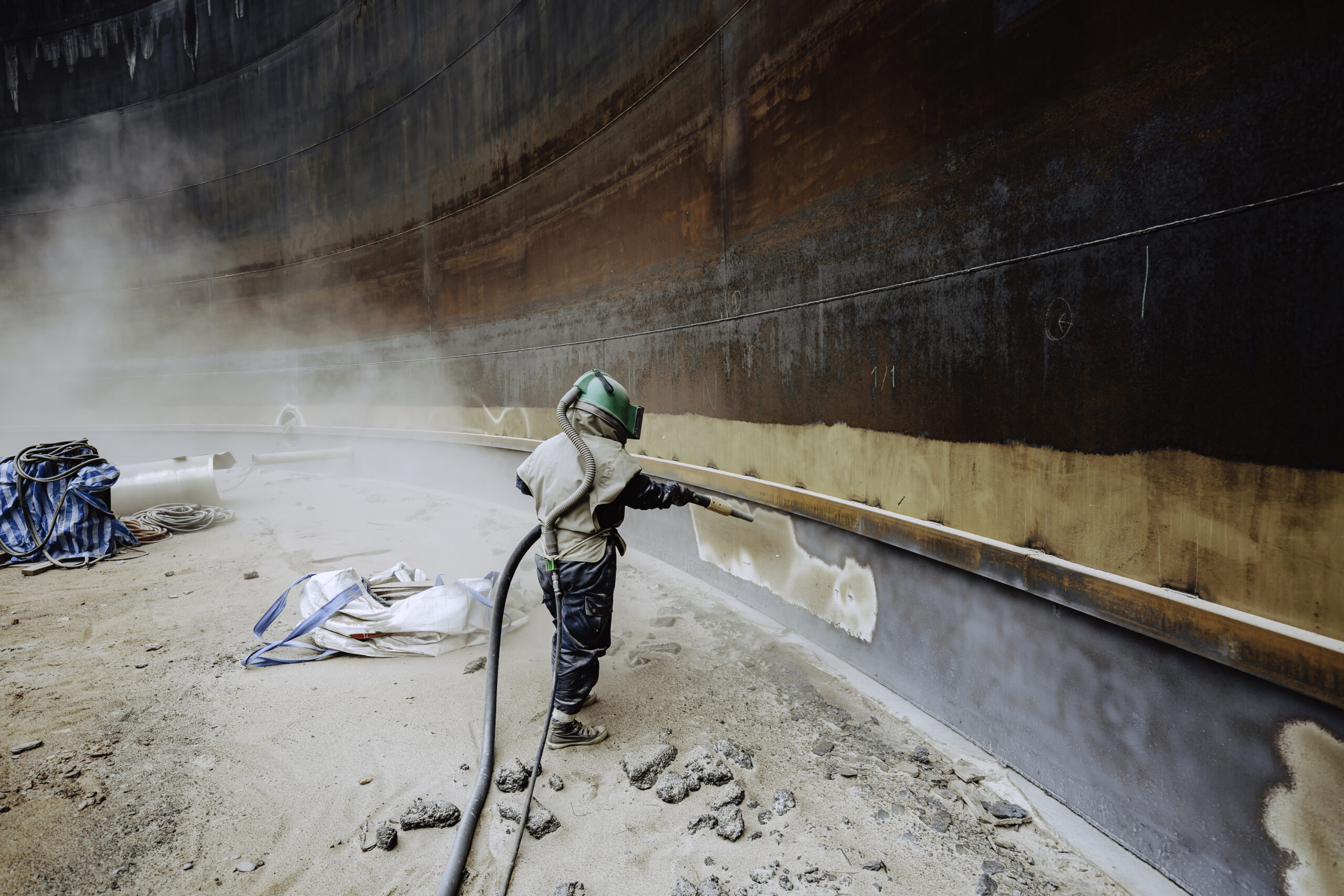 Female worker surface corrosion plate preparation by sand blasting of tank internal oil